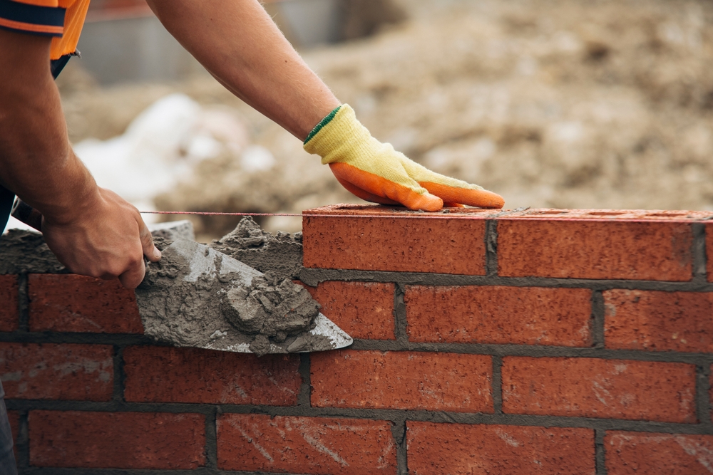 Construction,Worker,Laying,Red,Brick,With,Trowel,And,Mortar